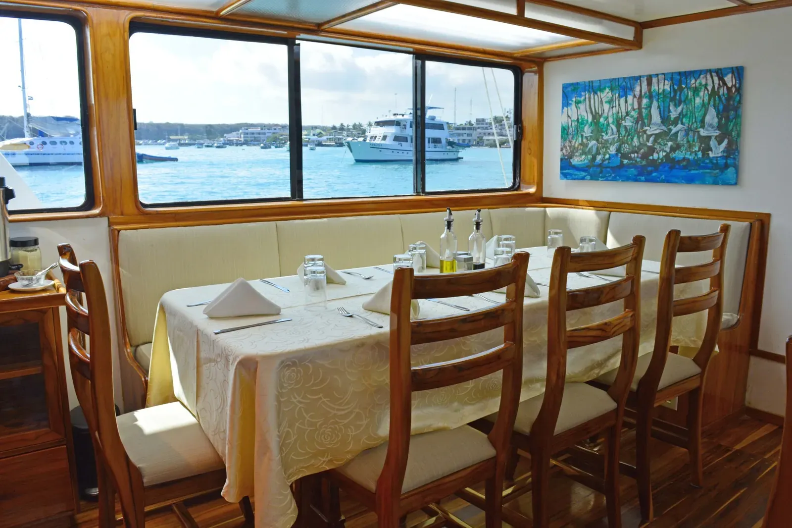 Matsal ombord på Eden i Galapagos med dukat bord och utsikt över hamnen.