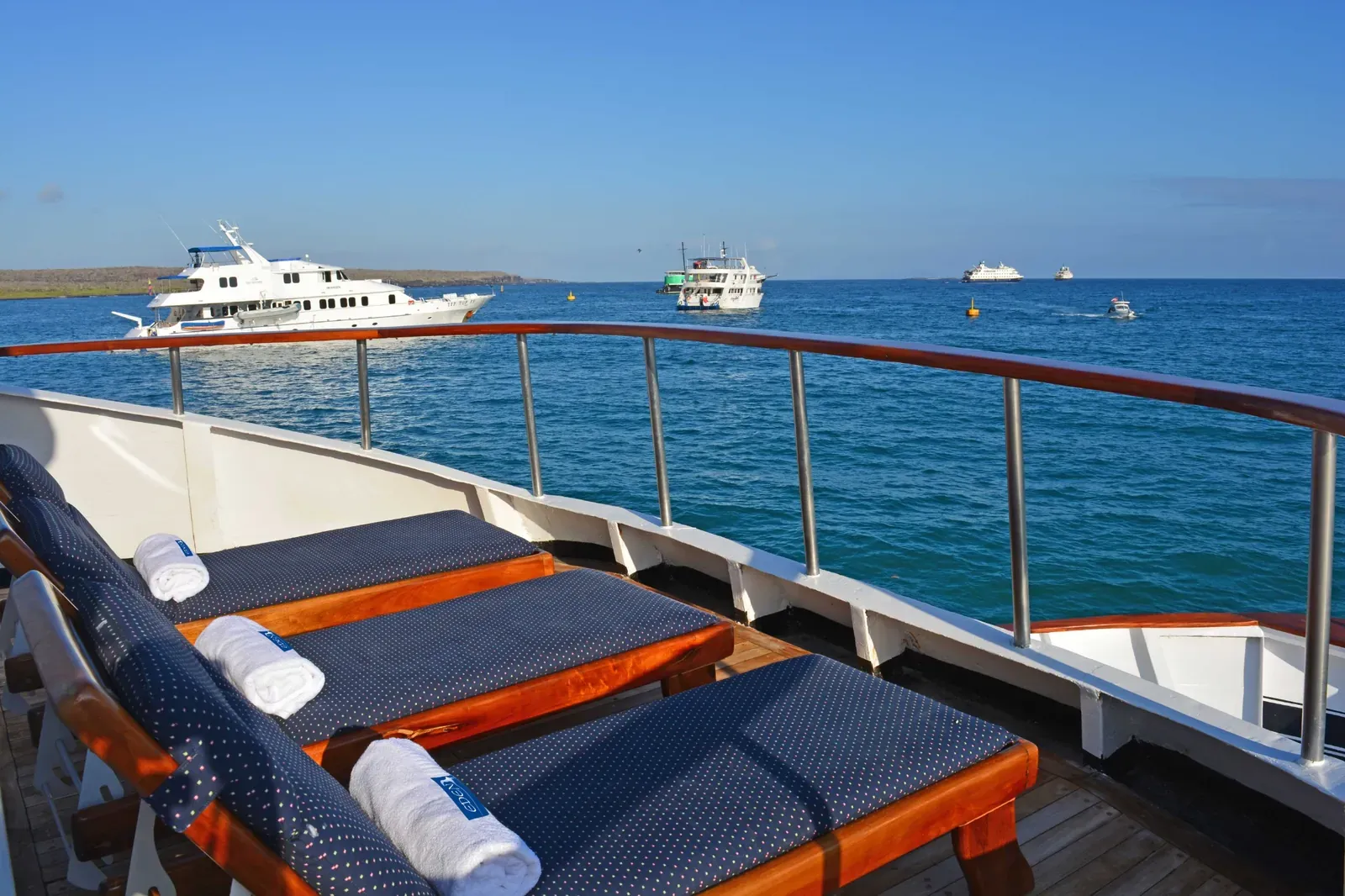 Solstolar på övre däck ombord på Eden i Galapagos med utsikt över havet.